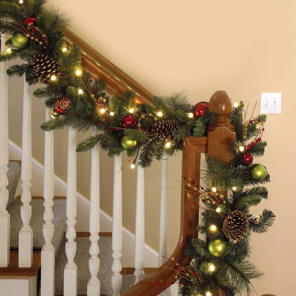 Staircase decorations with lights, leaves, and shiny balls for Christmas