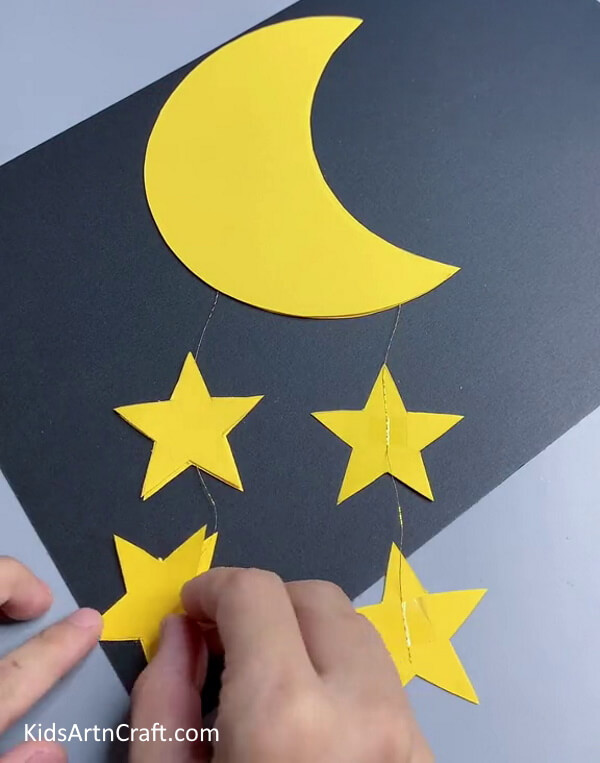 Pasting The Other Set Of Stars To Seal The Thread- Building a Wall Display with Paper Moons and Stars for Tots