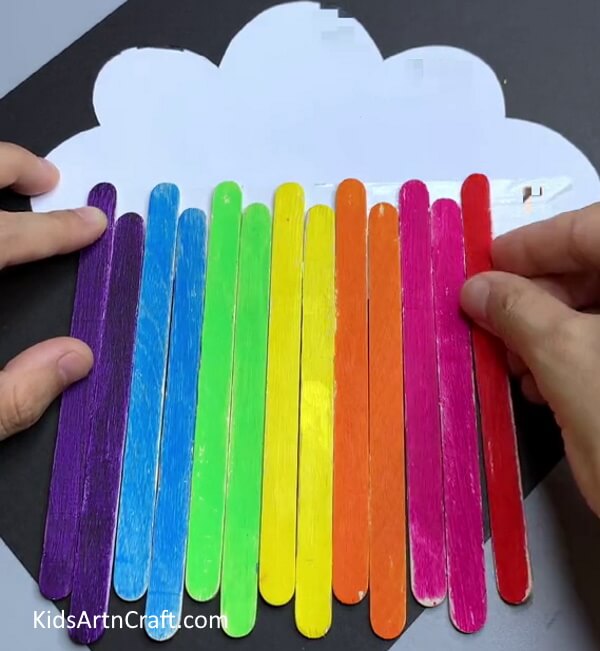 Pasting All Sticks On Cloud - Cute Paper Cloud Rainbow Construction For Kindergarteners To Create