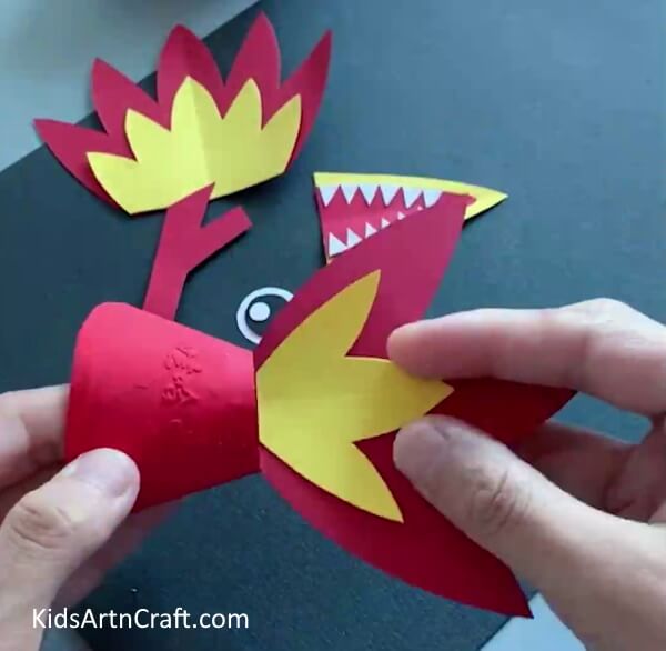 Pasting Tail On Bottle - A straightforward craft project utilizing paper and plastic containers to create a dragon for children. 