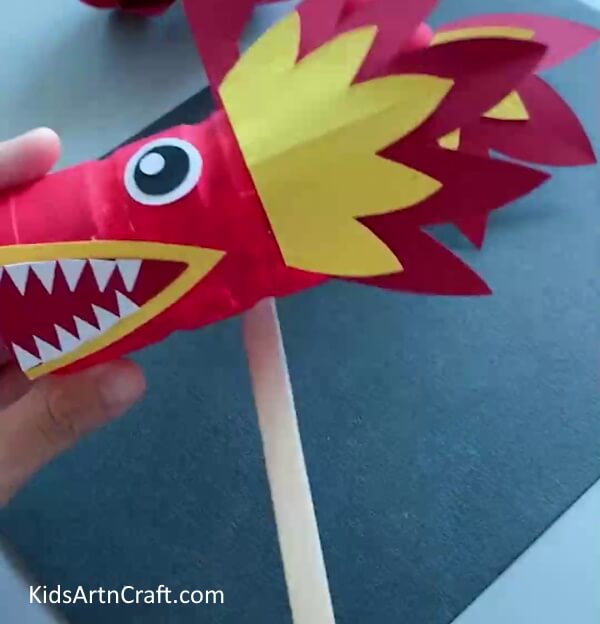 Adding Popsicle Stick - An amusing and effortless craft for youngsters to make a dragon out of paper and plastic containers. 