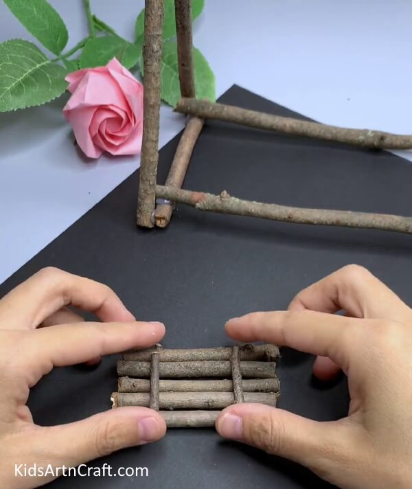 Making A Small Bundle Of Wooden Sticks - A tiny swing put together with a wooden stick, made for kids to enjoy.