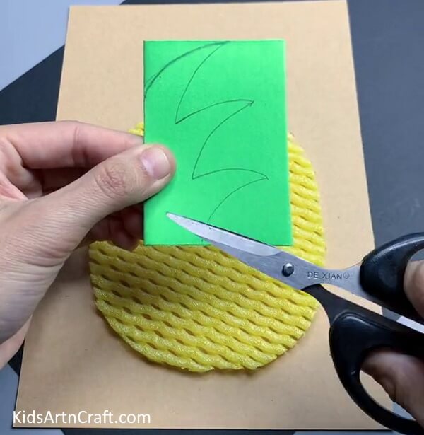 Cutting Leaf Out of Green Paper - Crafting a Pineapple Fruit Activity Using Foam Mesh
