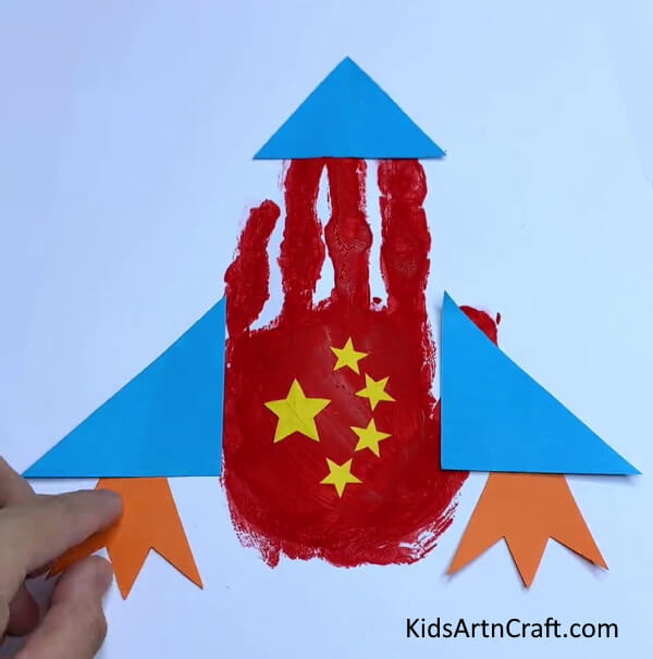 Pasting Orange Paper On the Left - Learning to Make a Handprint Paper Rocket - A Kids' Tutorial.