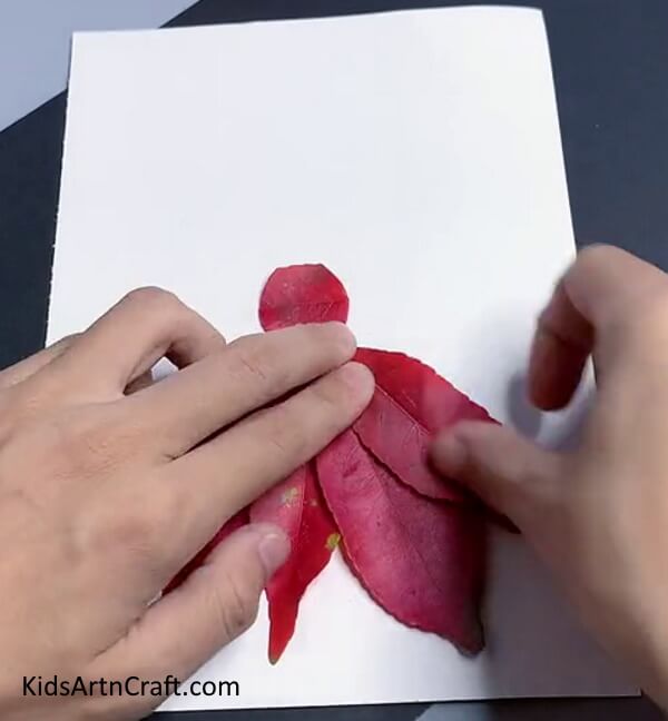 pasting leaves to complete dress. Creating the craft of leaf artwork for beginners