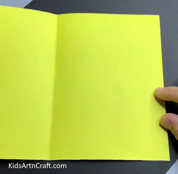 Folding Yellow Paper In Half - A straightforward paper sheep art project for children.