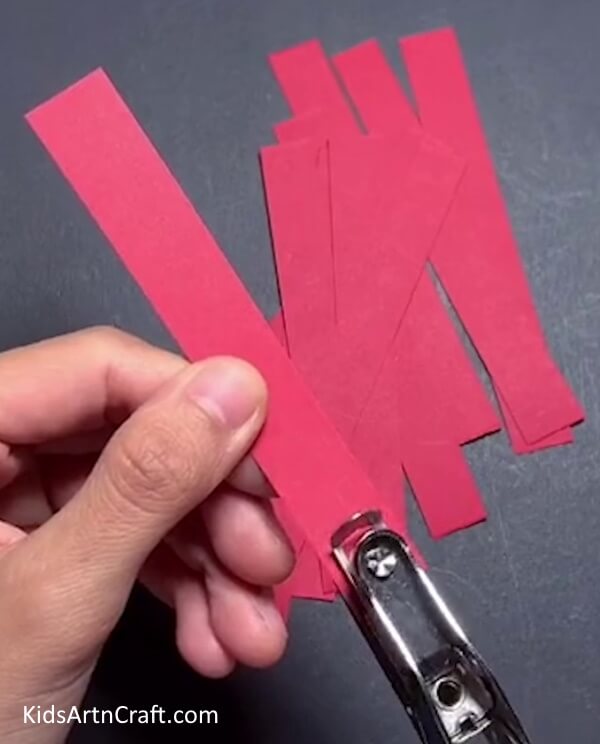 Punching The Strips - Teach your kids to make a paper strip apple craft.