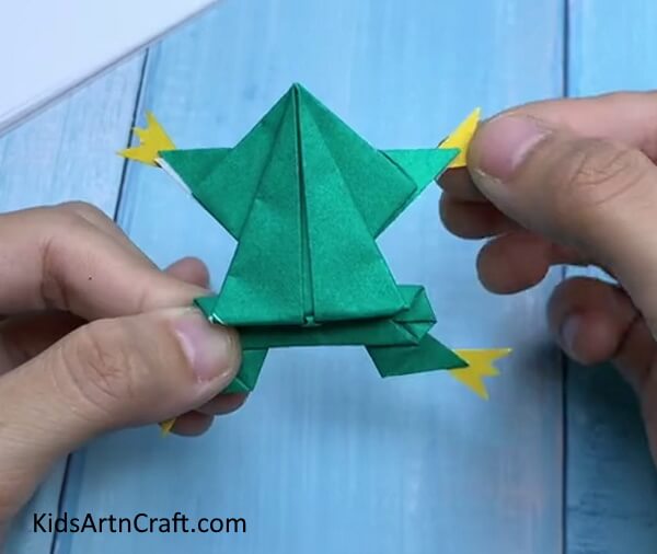 Adding Legs - Kids can learn how to fold paper into a frog with this origami tutorial. 