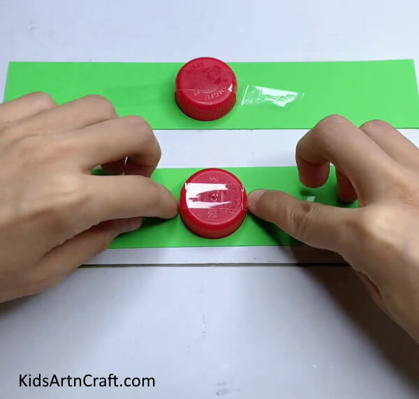 Applying Tape On Bottle Caps - Make a Frog Craft Utilizing Paper Strips On Your Own