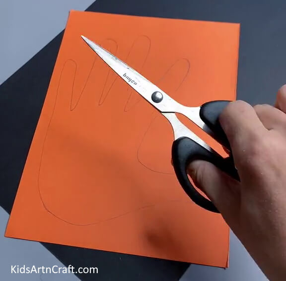 Drawing Hand On The Orange Paper- Children can create a Handprint Tiger craft.