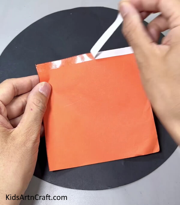 Applying Double Side Tape On Orange Square Paper Side - Simple Step-By-Step Guide to Making a Paper Carrot