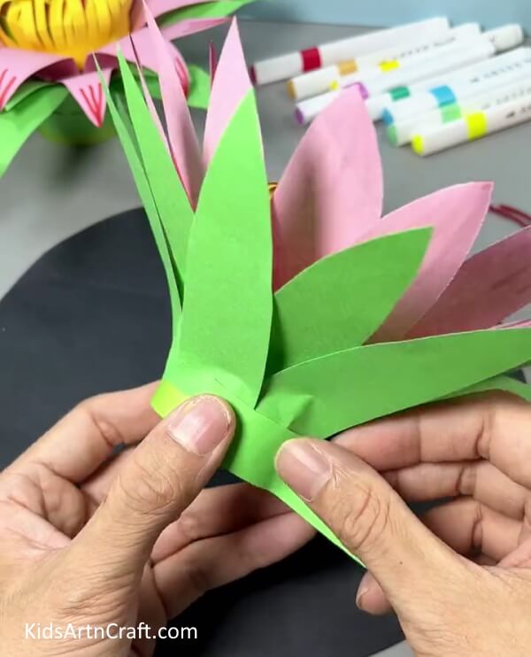 Pasting Green Paper Strip Around Paper Cup - Discover the Steps to Making a Paper Flower Hanging Craft