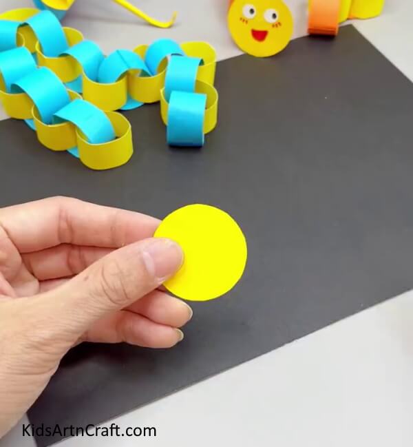 Cutting A Yellow Paper Circle - A kindergarten paper worm craft that can be created with ease.