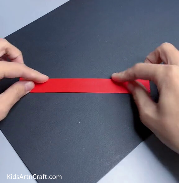 Folding In Half To Form Red Paper Strip - A Step-by-Step Guide to Making a Basic Paper Toy