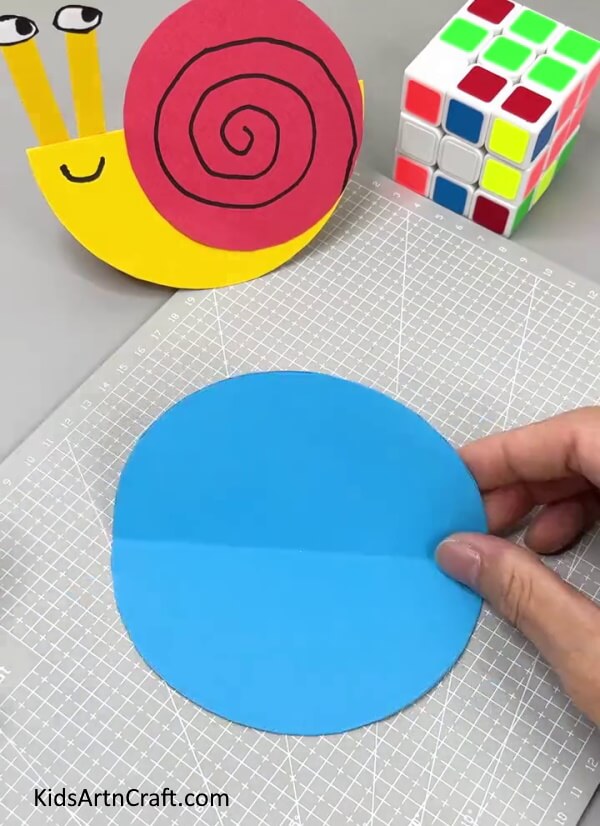 Cutting A big Blue Paper Circle - An easy paper snail activity that is perfect for children.