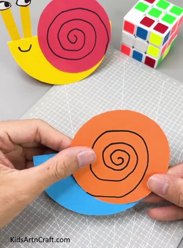 Pasting Orange Circle On Snail's Body - A simple way to make a paper snail with kids.