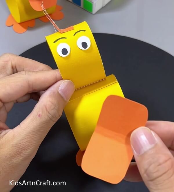 Taking An Orange Rectangle and Folding In Half - Crafting paper duck toys - an entertaining activity for kids. 
