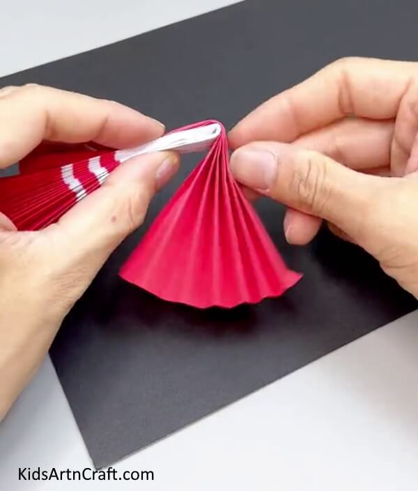 Folding Pink Strips Over White - Forming a Paper Doll Artwork For Infants