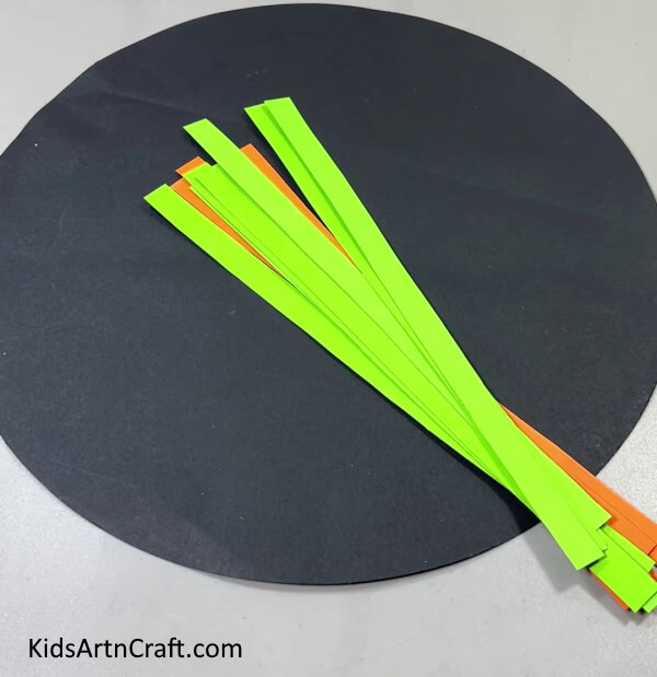 Cutting Orange And Green Strips And A Black Circle - Instructions for creating a Paper Strand Boat for Kids