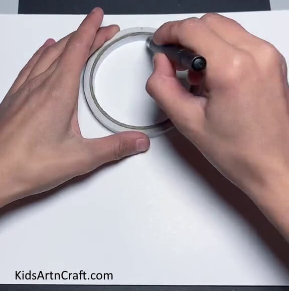 Drawing A Circle With The Help Of Tape Giving shape to a paper bunny craft in a straightforward manner 