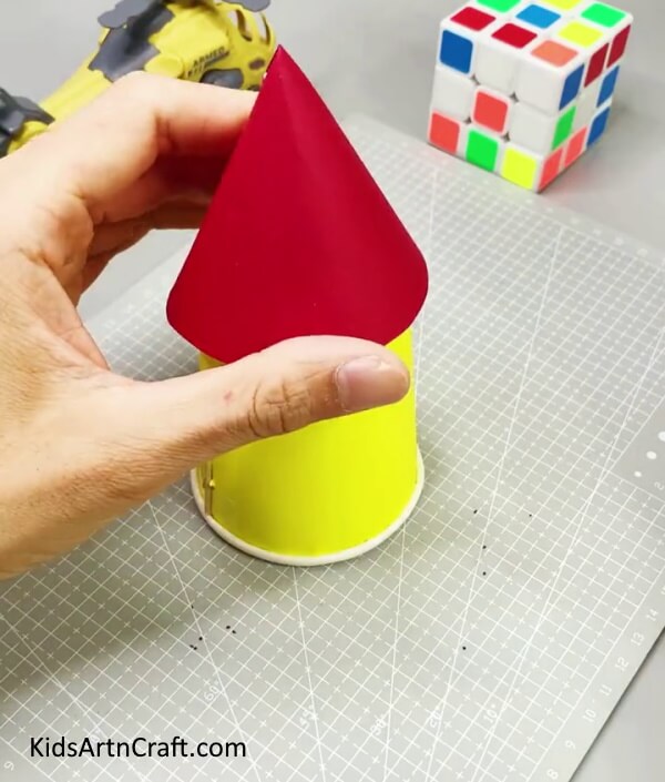 Pasting The Cone On The Paper Cup -An imaginative project for kids to revamp paper cups into a rocket. 