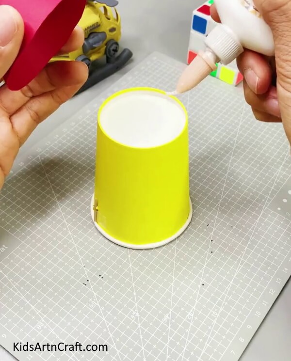 Applying Glue On The Bottom Of The Paper Cup -Redoing paper cups to produce a rocket craft for children. 