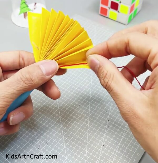 Placing Thread On the Side Fold Of the Fan - Making a Paper Fan Toy Craft for Kids to Have Fun With