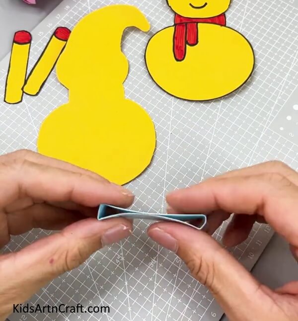 Pressing The Blue Strip From The Middle -DIY paper snowman craft tutorial for kids to follow