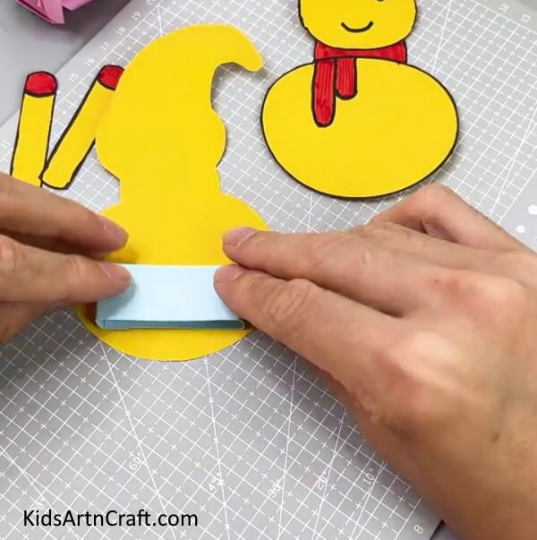 Pasting The Blue Strip On The Snowman -Tutorial to help children make a snowman using paper