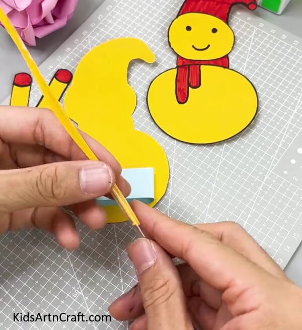 Cutting A Yellow Strip And Inserting It Into A Plastic Straw - Instructions for kids to make a paper snowman using DIY approaches