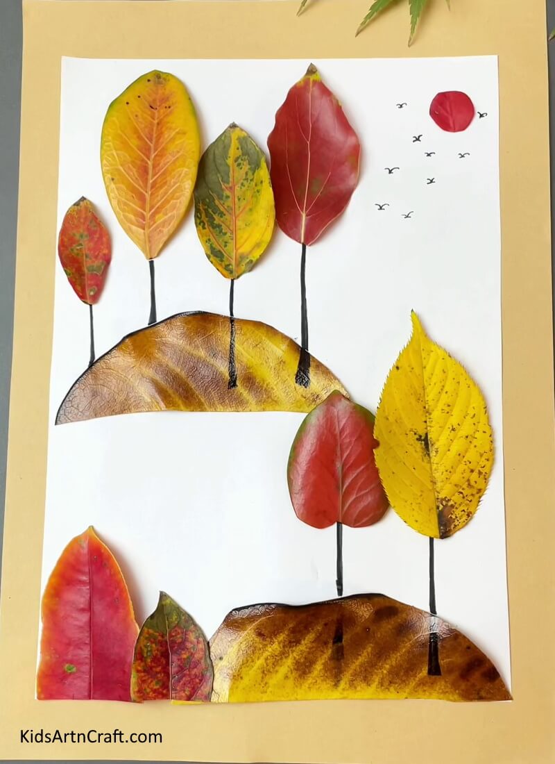 Here is the final piece after sticking all the leaves, sun and drawing birds in the white paper- Simple Guide To Making Fall Leaves Art For Little Ones