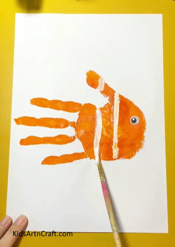 Painting white lines to make strips of the fish- Crafting Handprint Fish - A Tutorial for Newbies