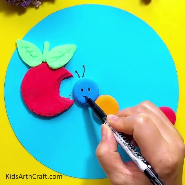 Draw the eyes, smile and antennae- Creating a Clay Scene of a Caterpillar Eating an Apple 