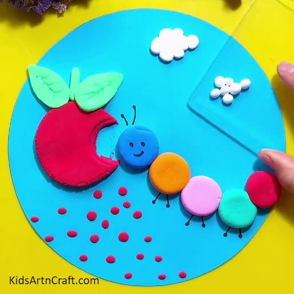 Place circles of white dough and press using paper weight- Carving a Clay Representation of a Caterpillar Eating an Apple 