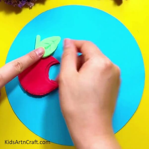 Place the leaf on the paper- Sculpting a Clay Representation of a Caterpillar Eating an Apple 