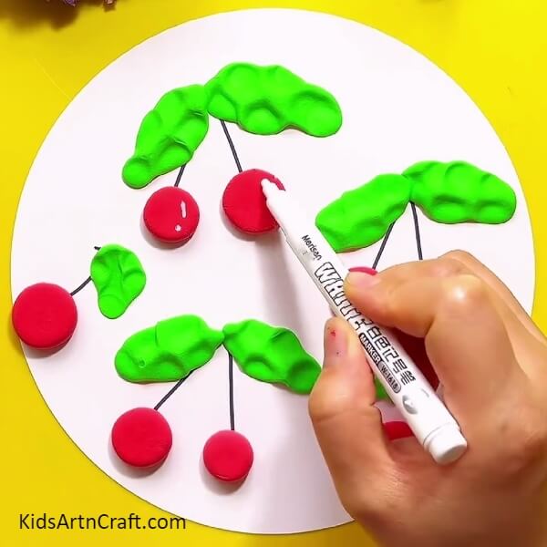 Making details of the cherries with white marker - Tutorial for Making Splendid Clay Cherries with Kids