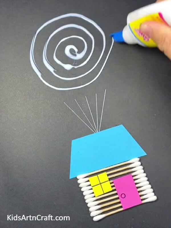 Applying glue on the black sheet to look Beautiful Flying House Balloon Craft Tutorial For Kids- A Tutorial on How to Create a Splendid Flying House Balloon for Children 