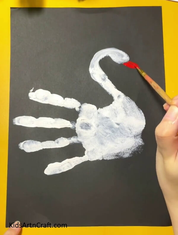 Painting the beak of the swan.- Gorgeous Handprint Swan Art Project For Learners