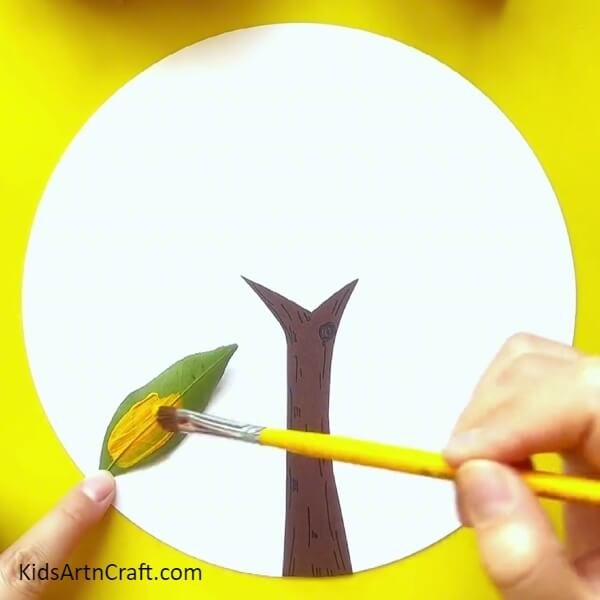 Applying Yellow Paint On The Leaf-Guide to producing a gorgeous tree painting with leaf imprints, specifically for kids