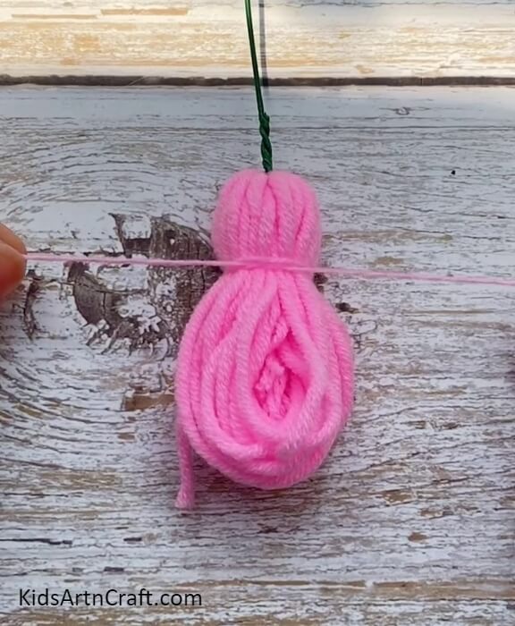 Cutting Small Piece Of Woolen Thread And Knot It With Roll Of Thread- Directions to Crafting Lovely Wool Blooms with Kids
