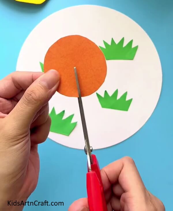 Making A Cut On The Orange Circle - A straightforward home activity to make Easter decorations with chickens.