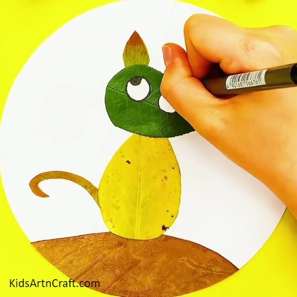 Add Details to the Cat’s Eyes- A Kid-Friendly Guide to Crafting a Cat Drawing with Leaves from Fall