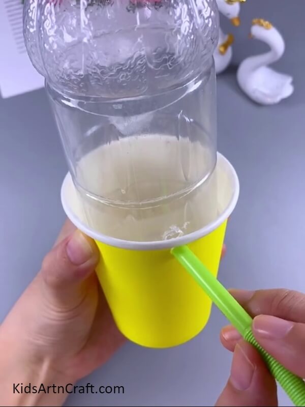 Inserting the straw in the holes- Follow this tutorial to show your kids how to make a sweet elephant water dispenser from a plastic bottle.