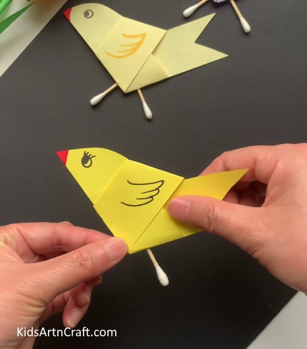 Pasting Earbuds To Form Legs - Assembling a paper and earbud bird-inspired craft.