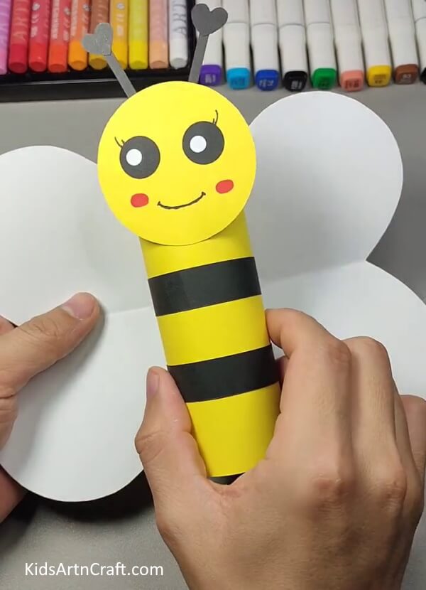 Pasting wings with bee's body- Building a Cardboard Cylinder Bumblebee Craft for Kids