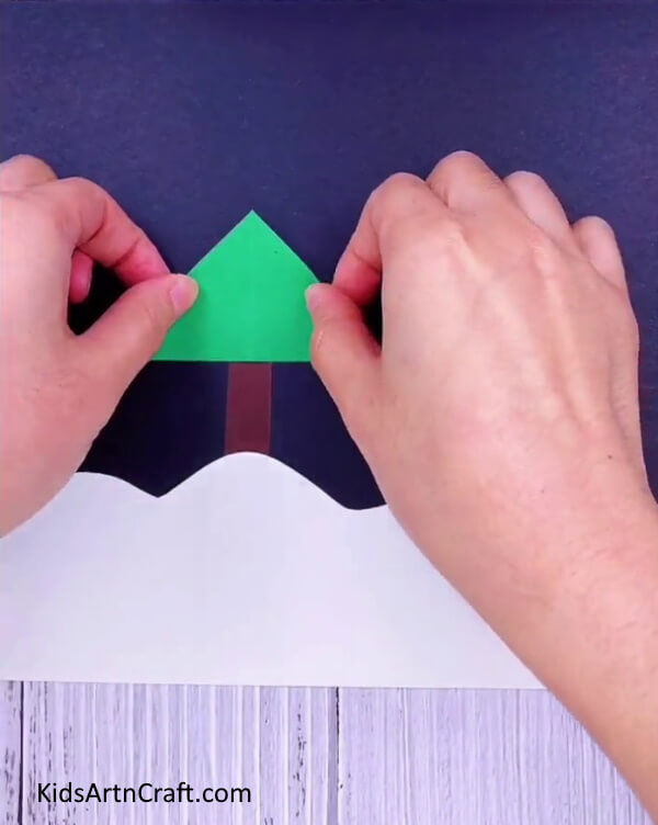 Paste a triangular cutout- Fabricate a Christmas Tree with your own resources for a joyful decoration.