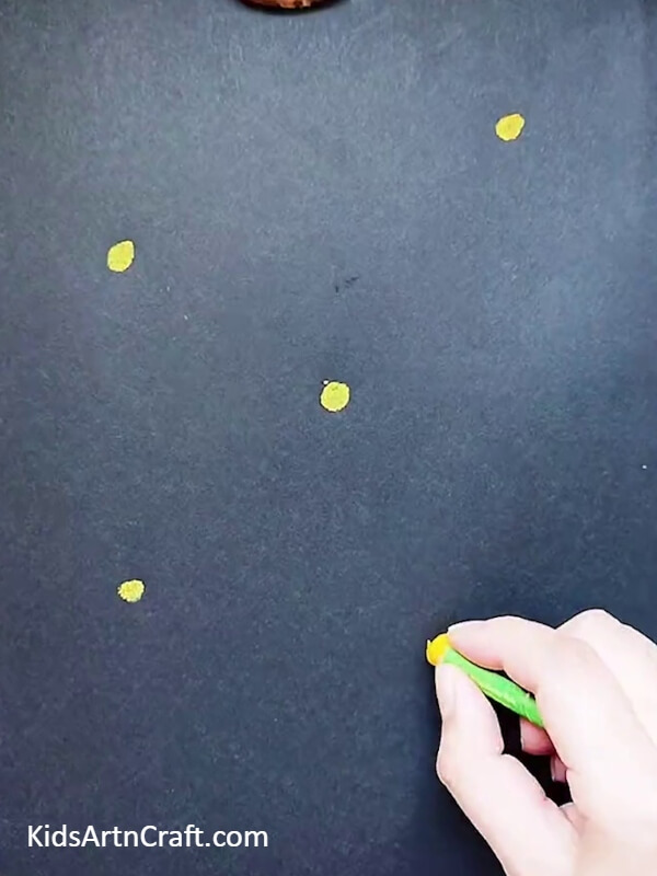 Now start by making small dots with yellow crayon in black paper- Crafting with Dandelions - An Artistic Activity for Little Ones