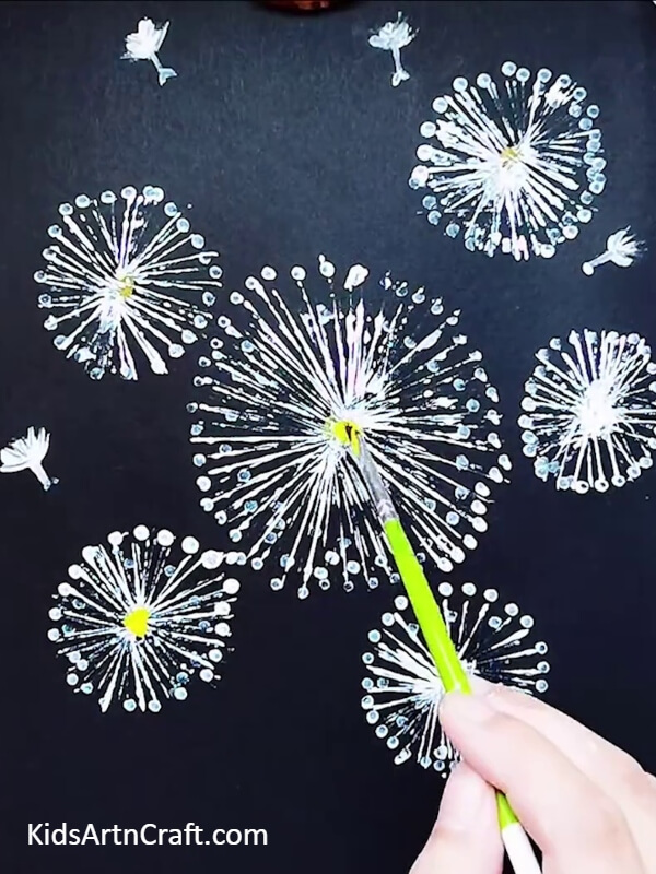 Making the dots in the middle with yellow paint- Let Kids Create a Masterpiece with a Dandelion Painting