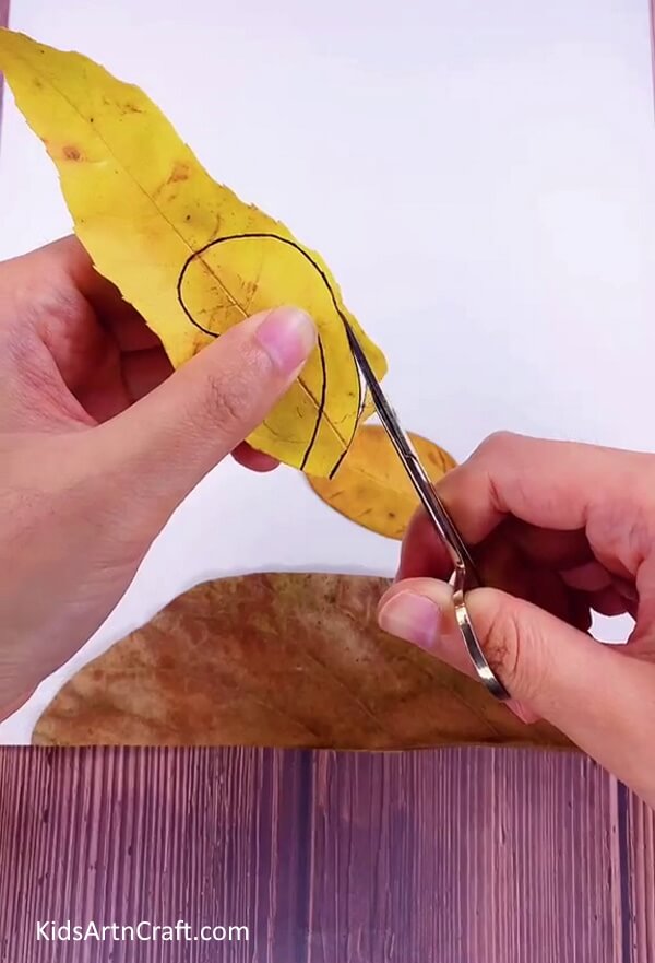 Cutting Head Piece From Yellow Leaf to Make a Leaf Dinosaur Easily at Home- DIY dinosaur making with leaves - it's easy with this tutorial for kids. 