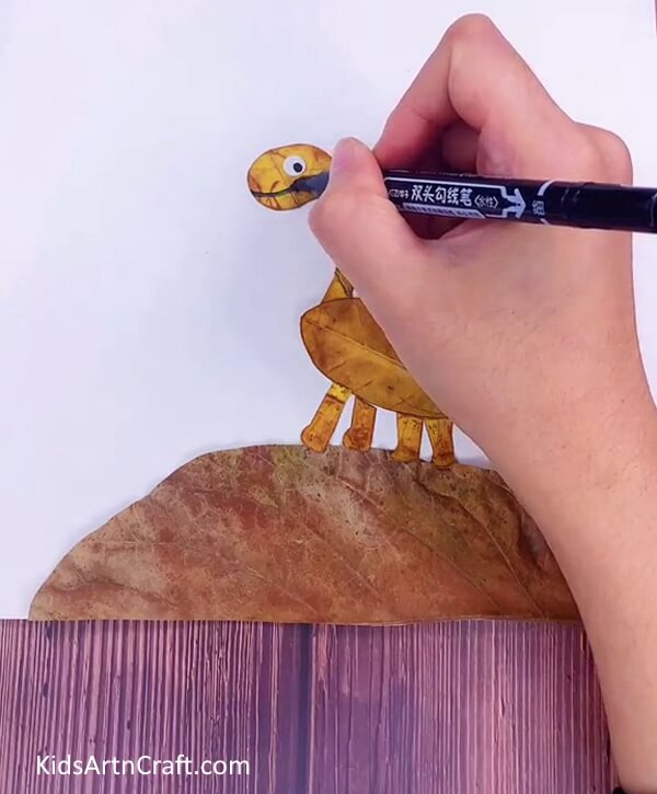 Pasting Eyes For Dinosaur to look real for kids- A fun activity for kids - make a dinosaur out of leaves with this tutorial. 